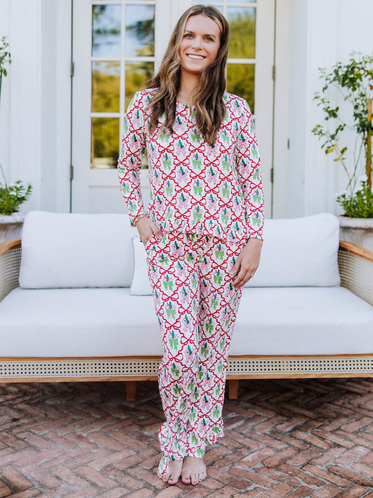 Women standing outside in front of couch wearing a matching ruffled pant set that has many different colorful bows on it.