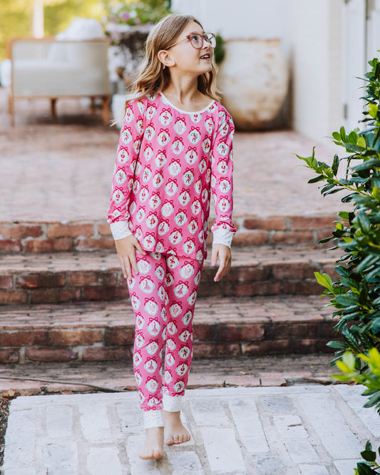 Girl walking outside on brick steps and is wearing a matching pair of fitted pajamas that have a pink nutcracker print on them.