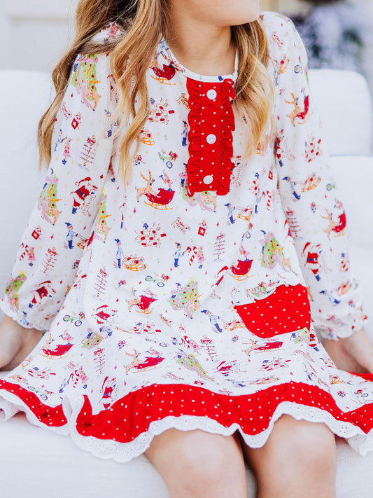 Girl sitting down wearing a dress that has a north pole print on it