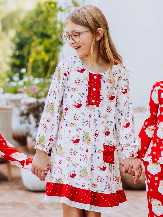 Girl outside holding hands and is wearing a play dress that has north pole print on it.
