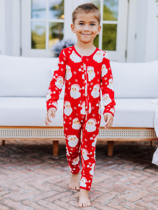 Child outside wearing a red santa layette.