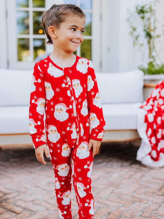 Child outside wearing a red santa layette.