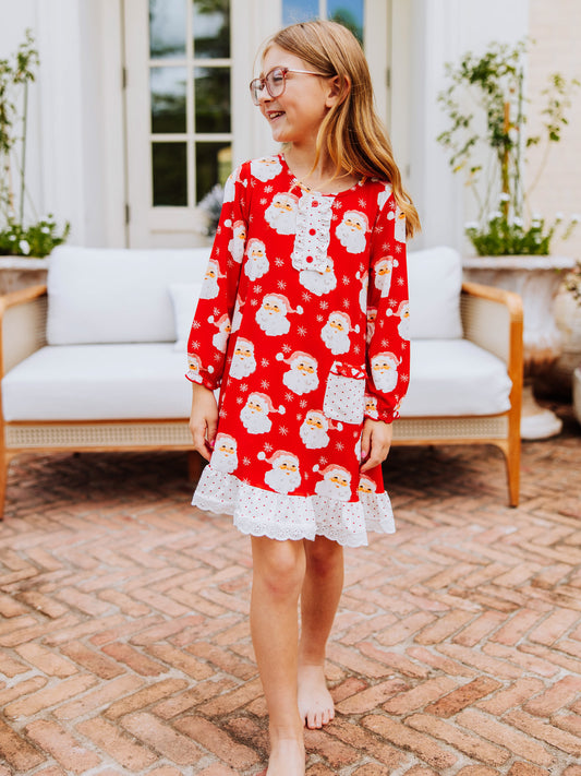 Girl walking outside on brick wearing a red santa dress.