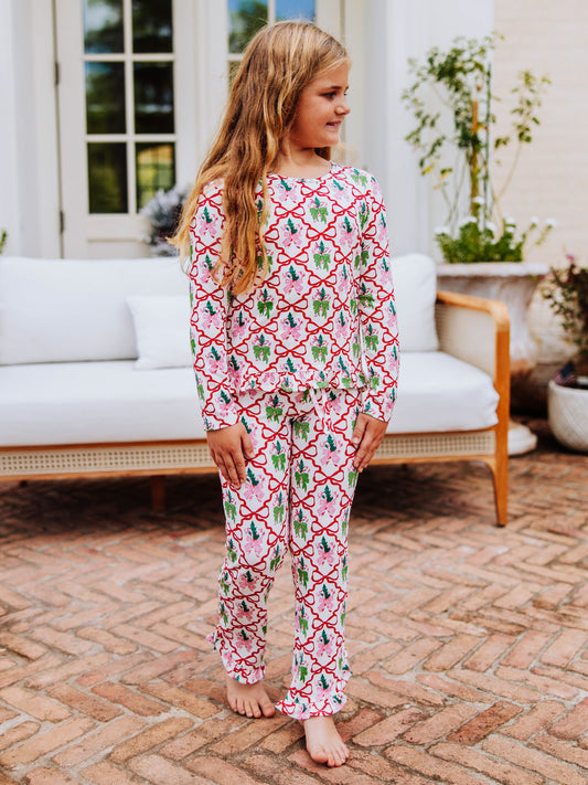 Girl standing on porch wearing a matching two piece set that has red bows all throughout.