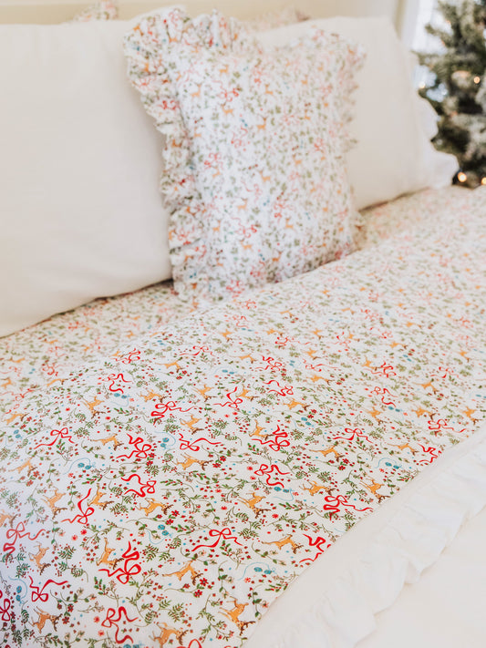 Holiday themed decorative pillow and sheet set with white pillows and duvet.