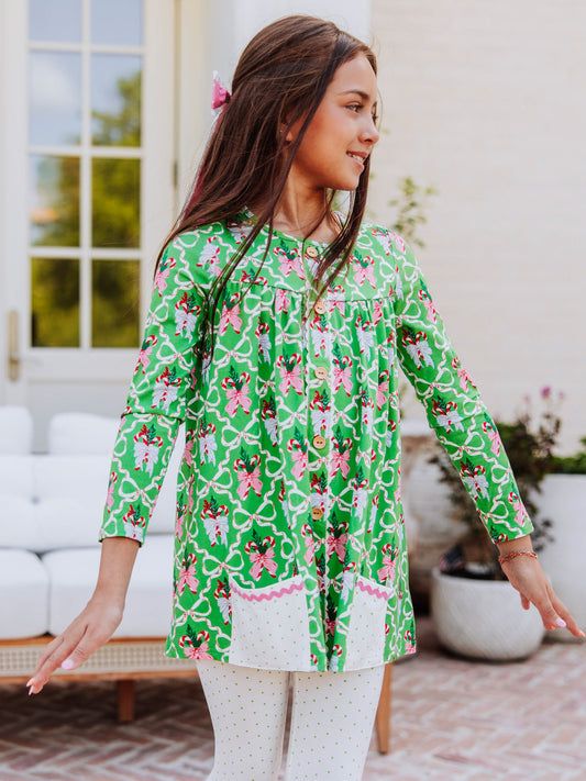 Girl outside wearing a holiday themed top with her arms out to her side.