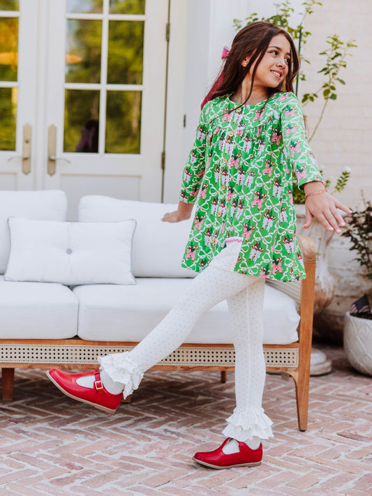 Girl kicking her leg out wearing a holiday themed outfit with red mary janes.