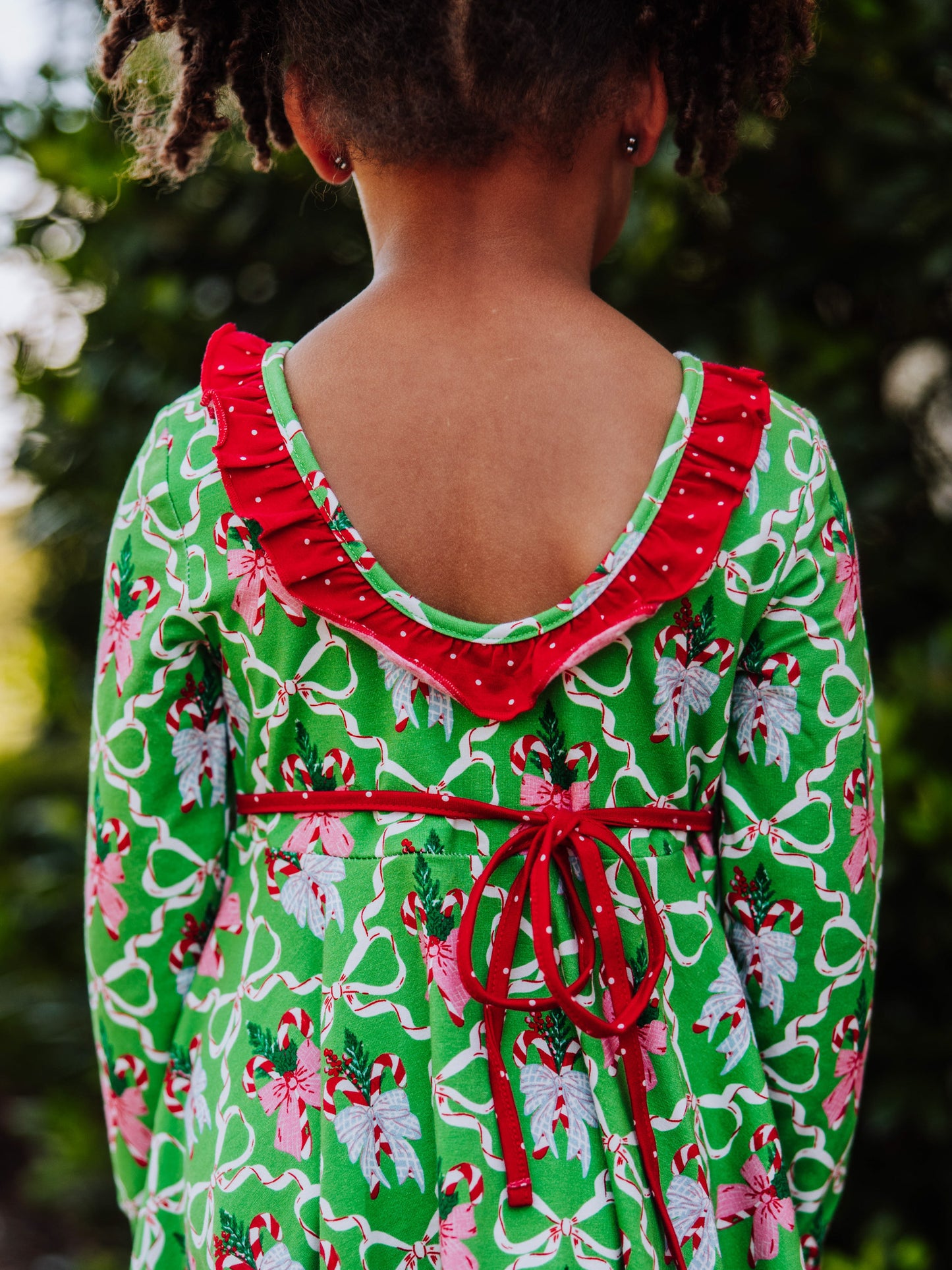 Back shot of the scoop back and ruffle detail on holiday patterned dress.