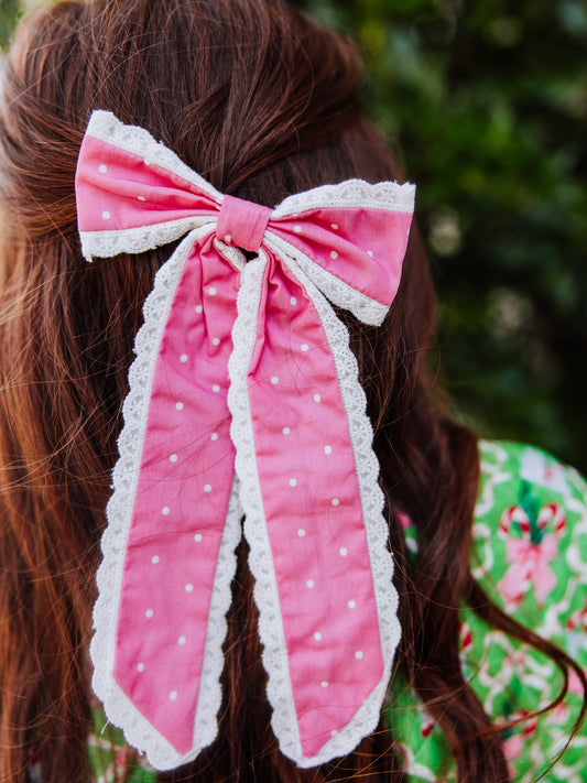 Pink long tail bow with white polka dots trimmed in dainty lace.