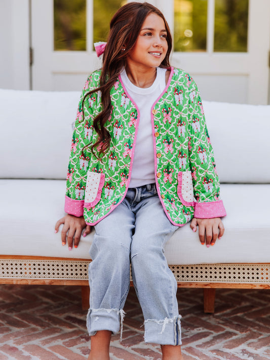 Girl sitting on couch wearing a quilted holiday themed cardigan with jeans.