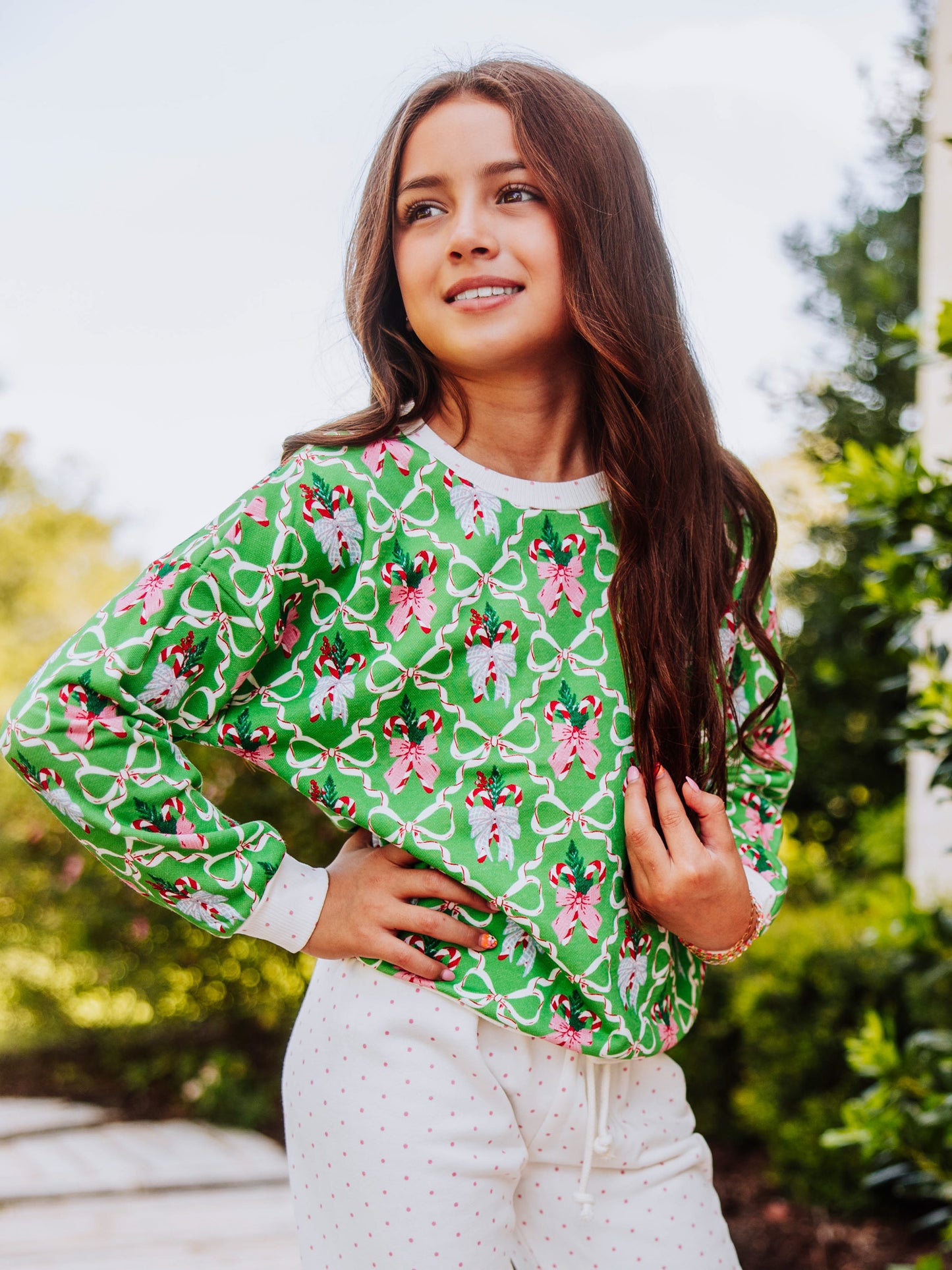 Girl standing outside with hands on hips wearing a holiday themed sweat set with tan clogs.