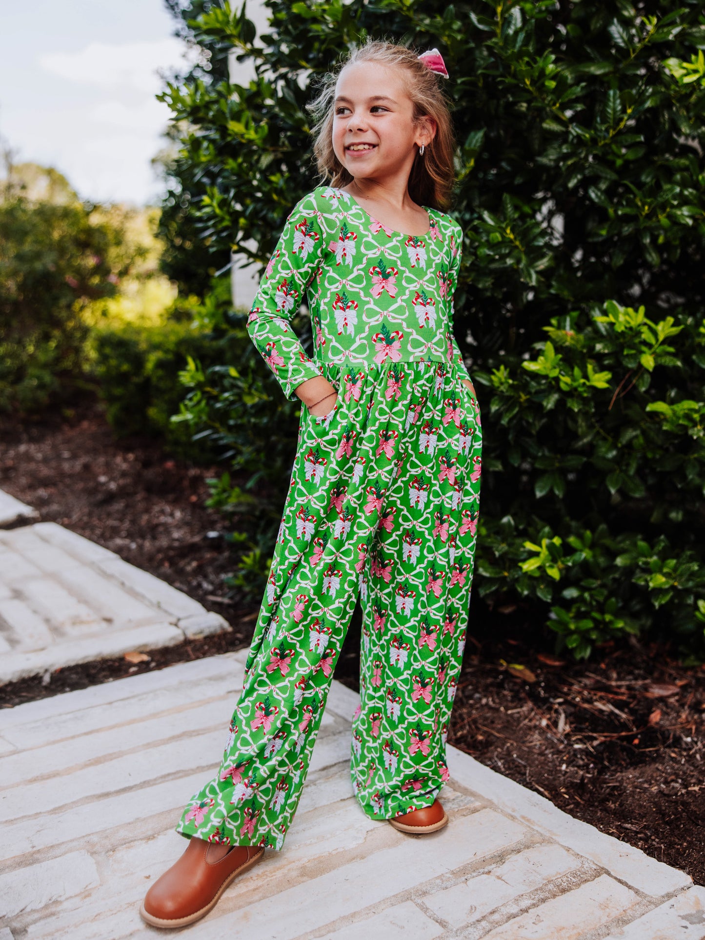 Model wearing a green bow holiday printed leggy romper.