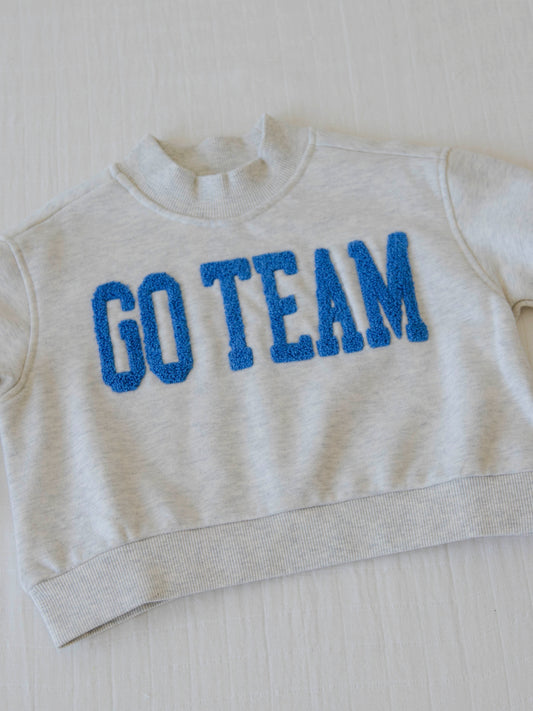 flay lay of a heathered gray sweater that says go team in royal blue