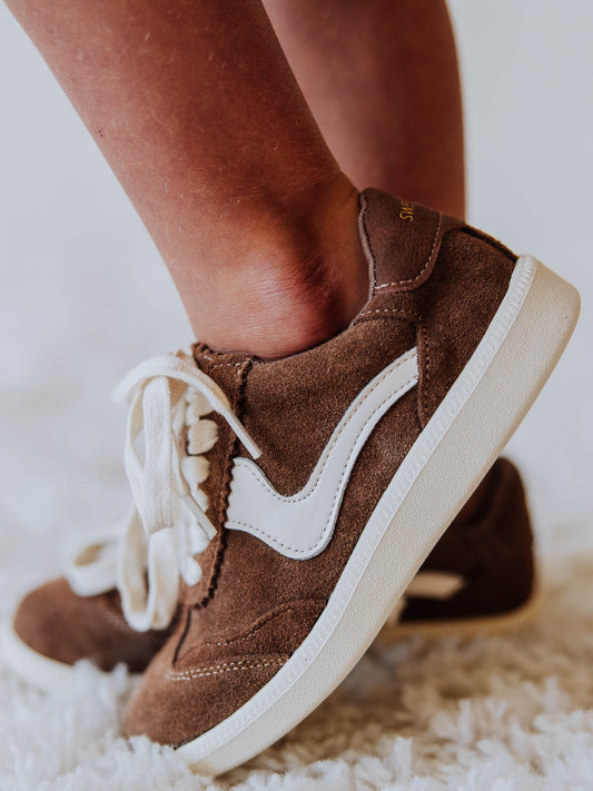 Brown mocha colored suede sneakers with a swish design on the side in a creamy white and creamy white laces.