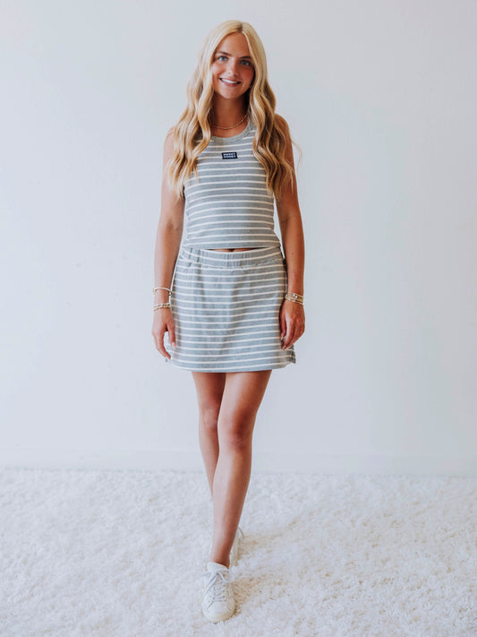 Model wearing a gray and white stiped skort set. Top has a Sweethoney stitched logo tag in the middle of chest