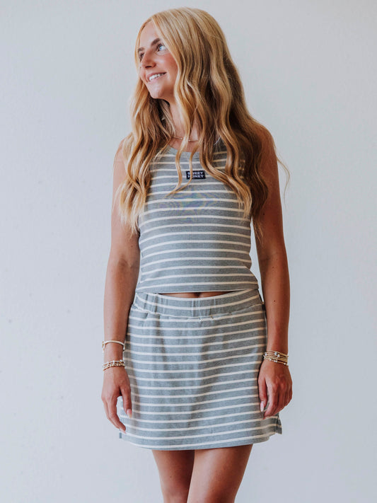 Model wearing a gray and white stiped skort set. Top has a Sweethoney stitched logo tag in the middle of chest