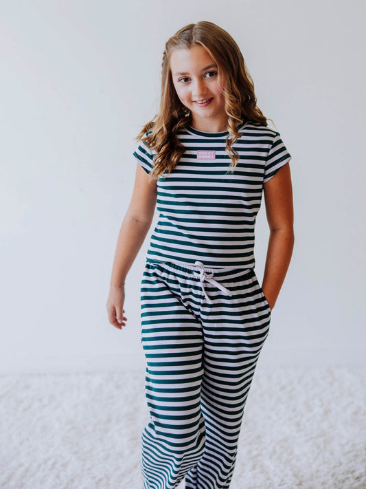 Girl is wearing a two piece, green and gray striped pant set and has hand in pocket