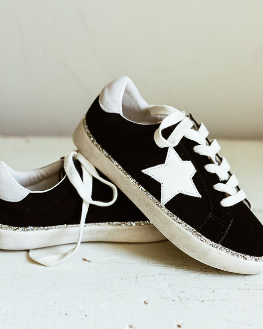 Black suede shoe with white star and glitter accents around shoe