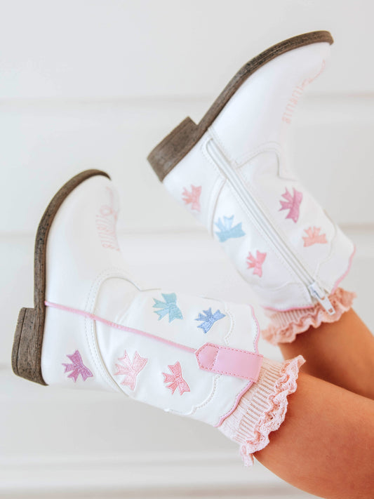 Step into sweetness with our Girls Bow Paneled Cowboy Boots, designed for twirls, giggles, and all-day play. These white faux-leather boots feature pastel pink, blue, and lavender star embroidery, charming bow panels, and an easy side zipper closure for quick on-and-off. With a soft interior lining and sturdy sole, these girls’ Western boots perfectly blend comfort and style—ideal for everyday wear, special occasions, or matching with her favorite SweetHoney dress.