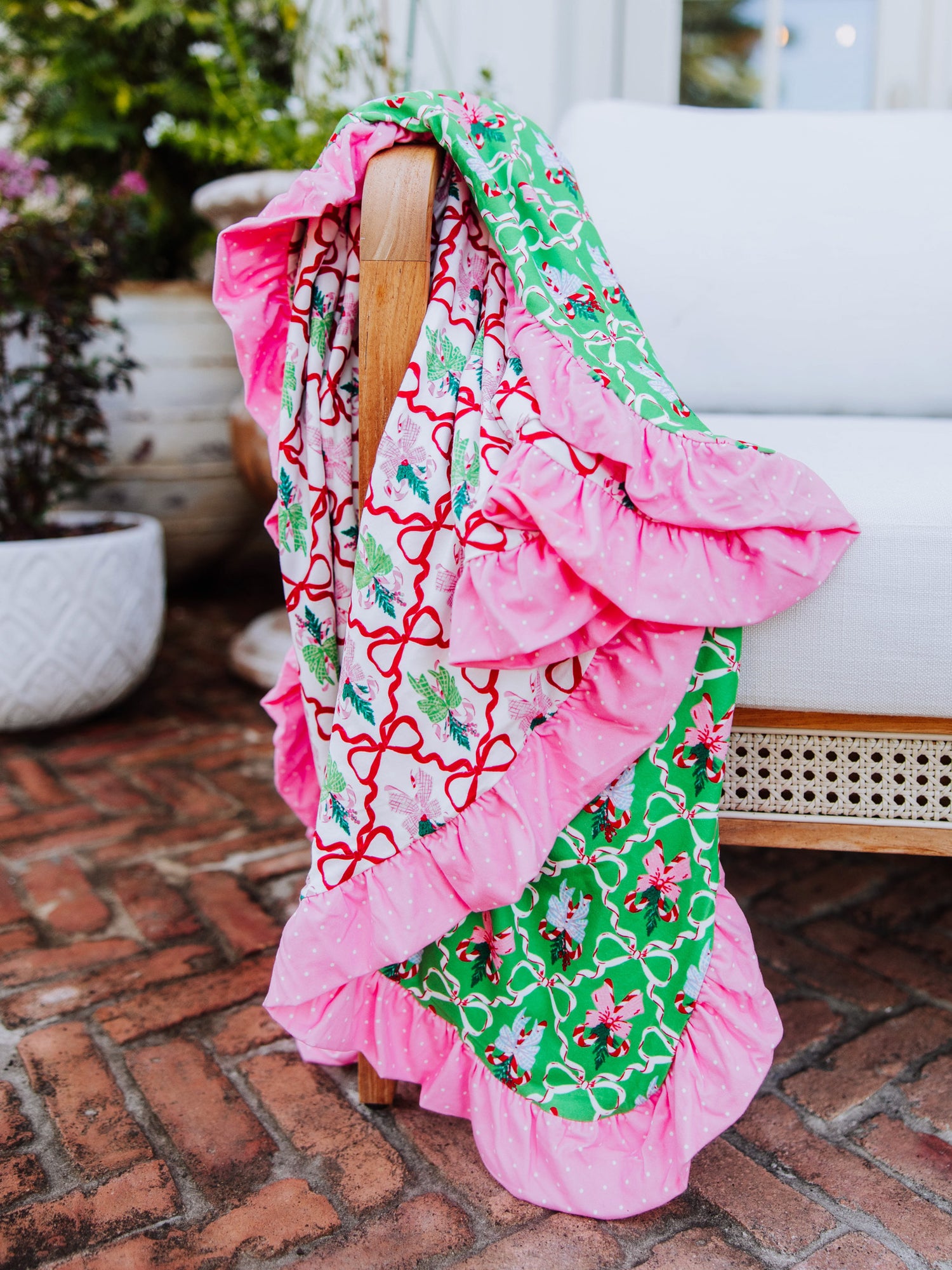 Colorful red, pink and green blanket draped over the arm of a couch. 