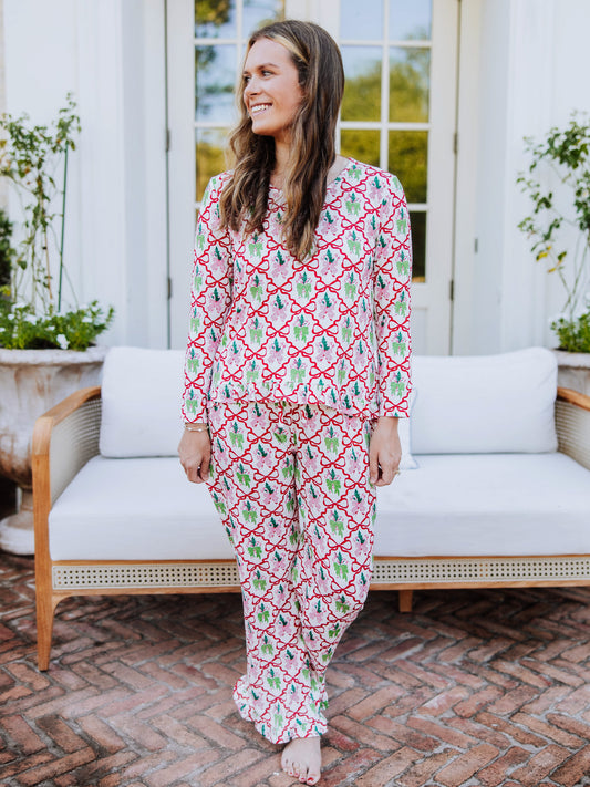Women standing outside in front of couch wearing a matching ruffled pant set that has many different colorful bows on it. 