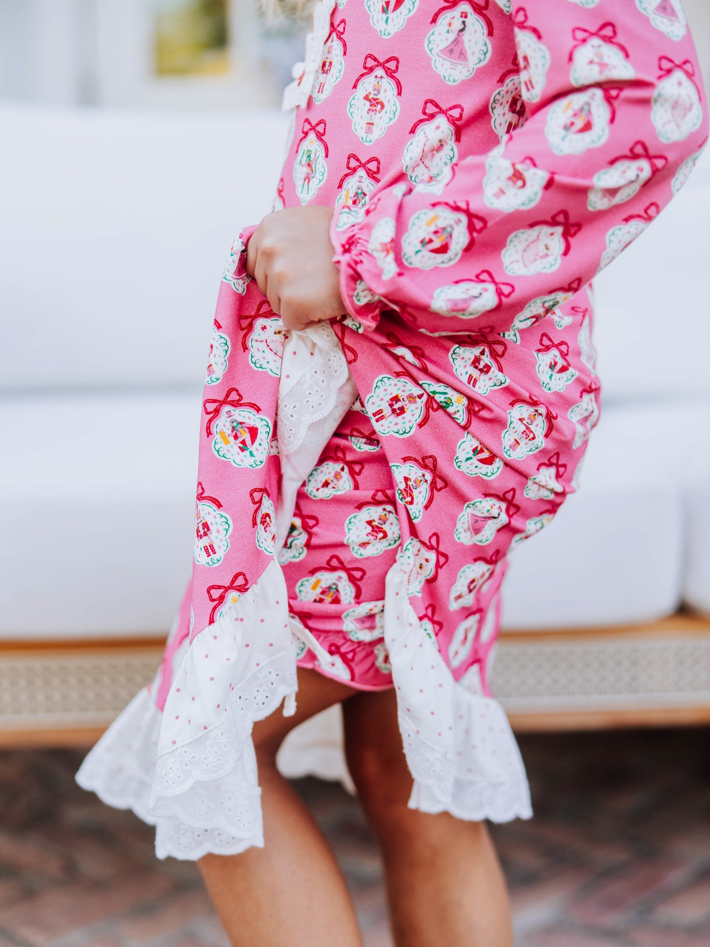 Model is wearing a pink nutcracker dress and is holding up the side of the dress to show the matching bloomers underneath