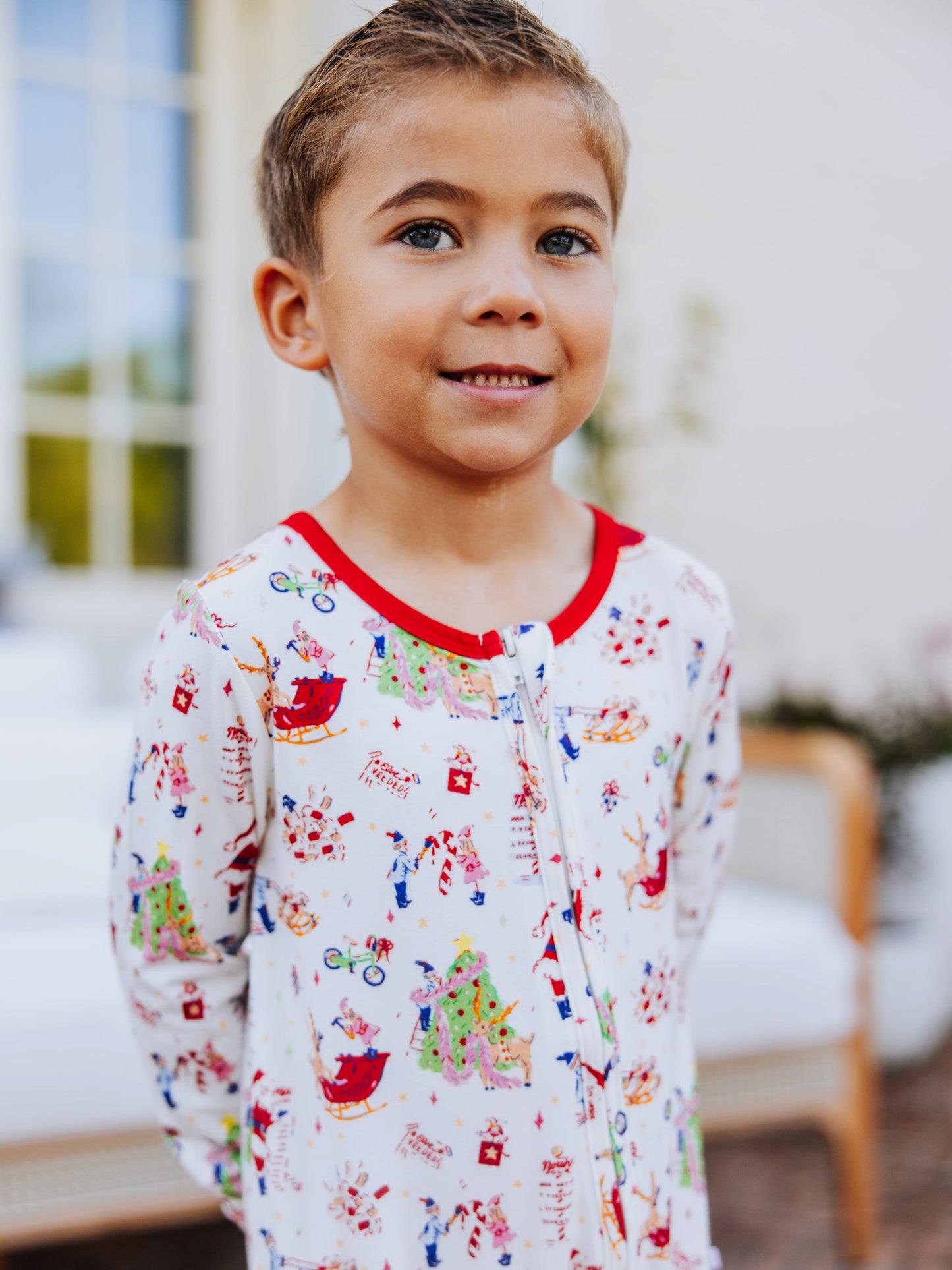 Close up of boy smiling wearing a north pole printed layette. 