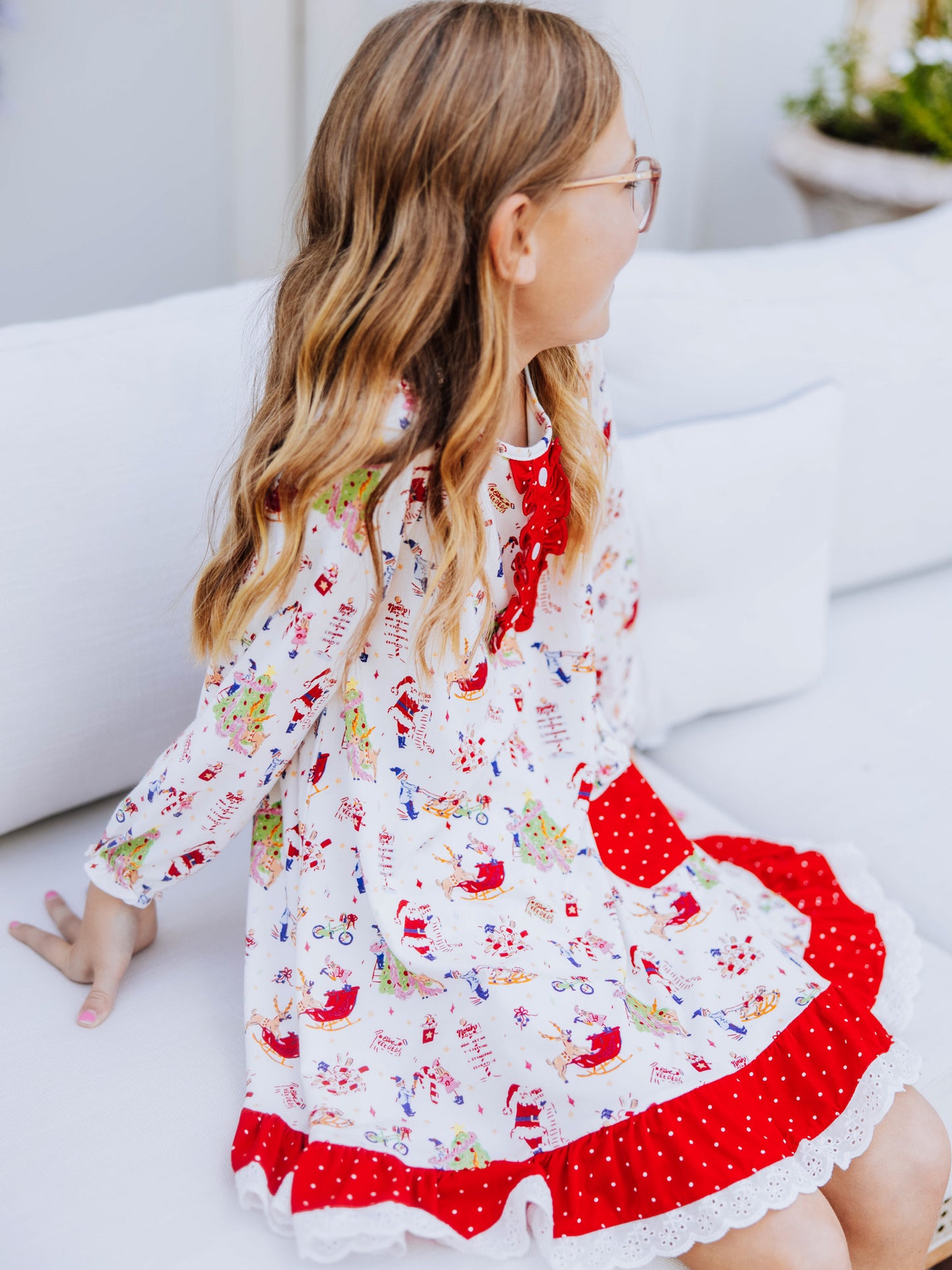 Girl sitting down wearing a dress that has a north pole print on it