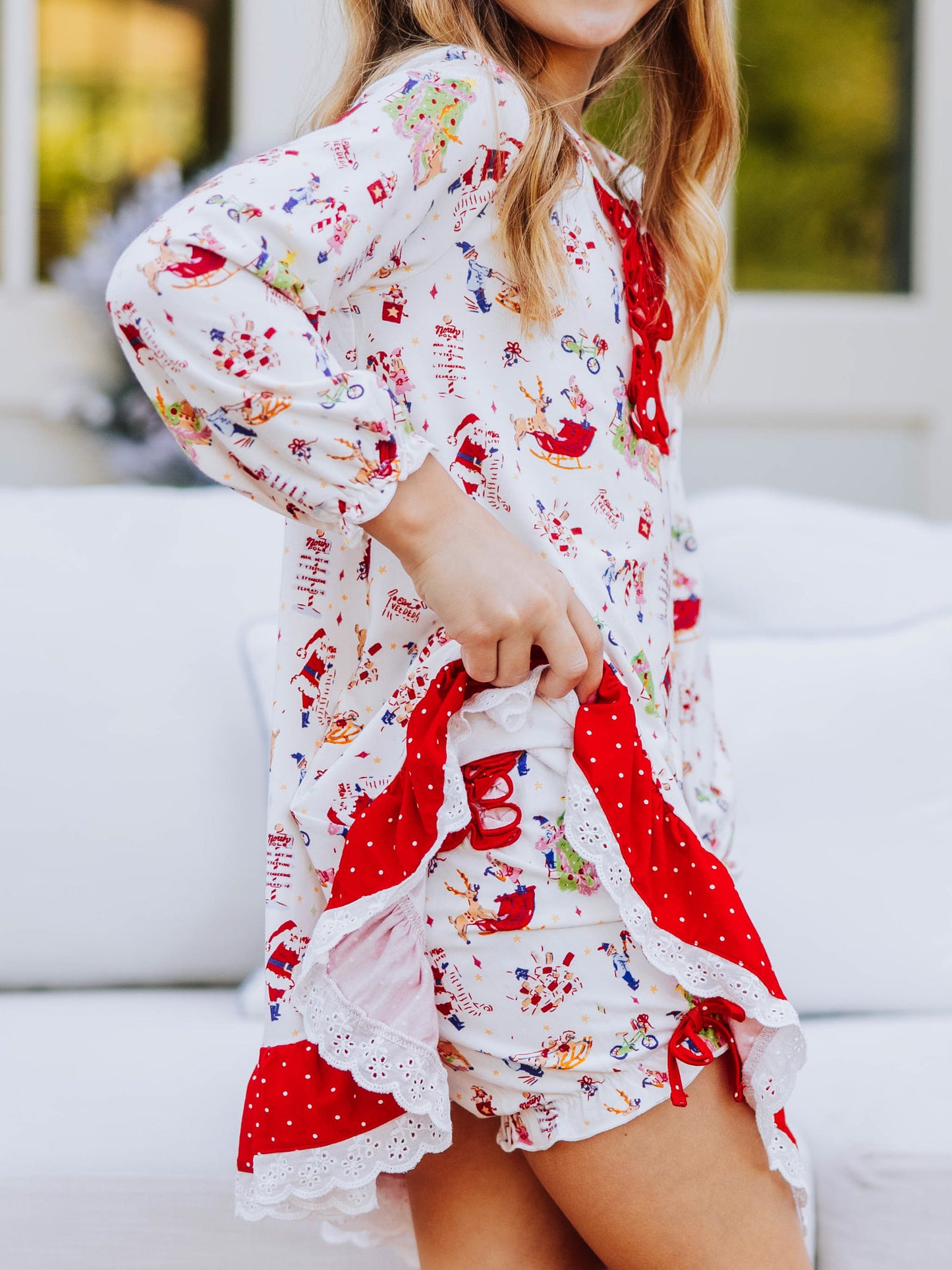Girl outside wearing a north pole play dress and is holding up one side of the dress to show the matching bloomers underneath