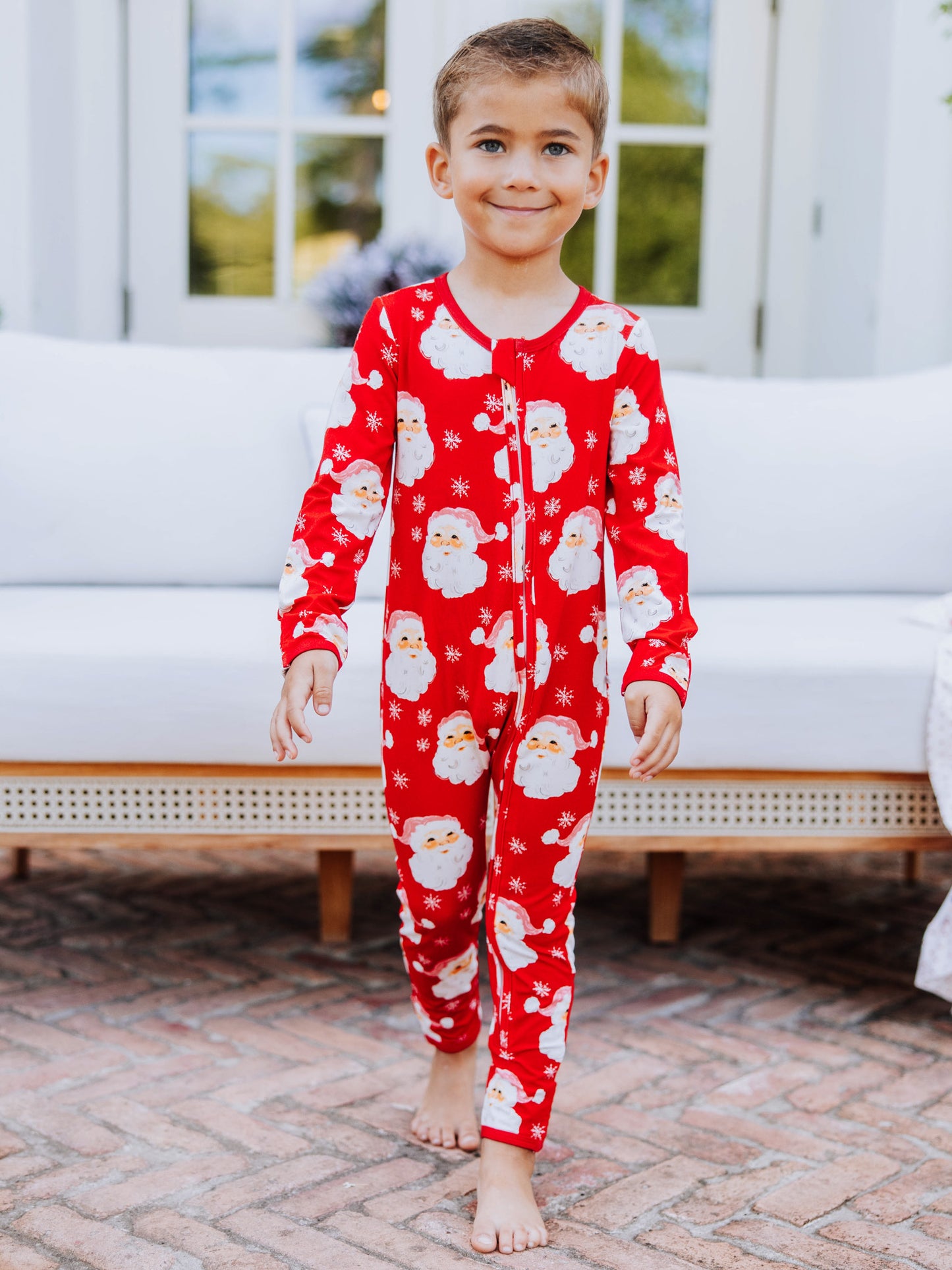 Child outside wearing a red santa layette. 