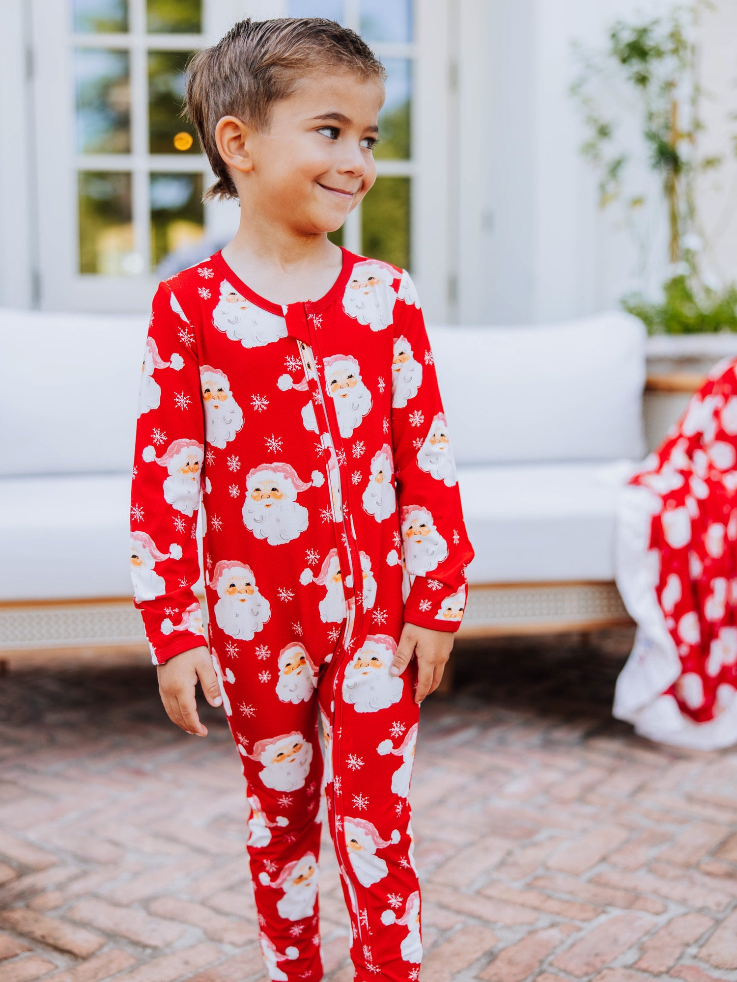 Child outside wearing a red santa layette. 