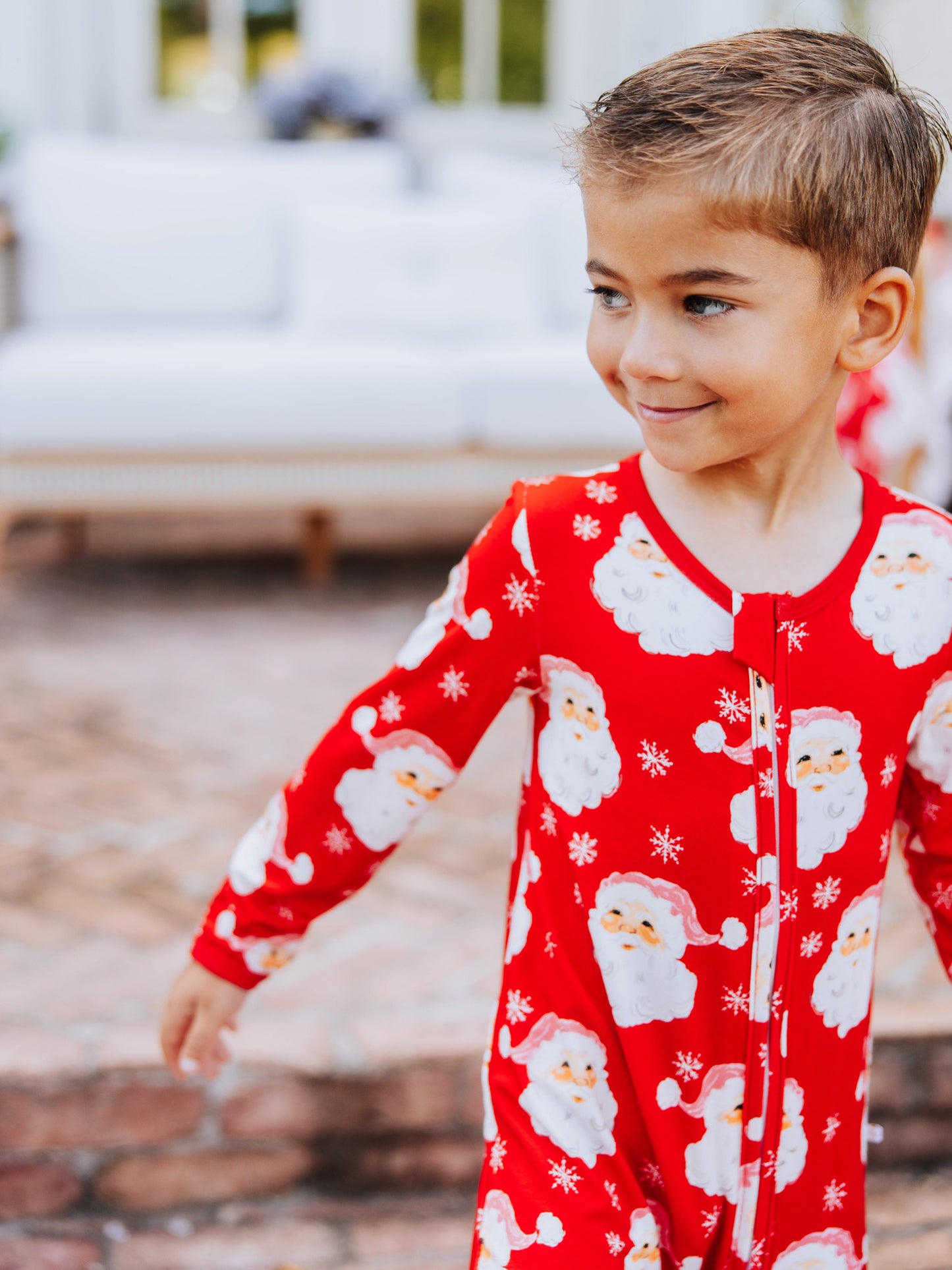 Child outside wearing a red santa layette. 