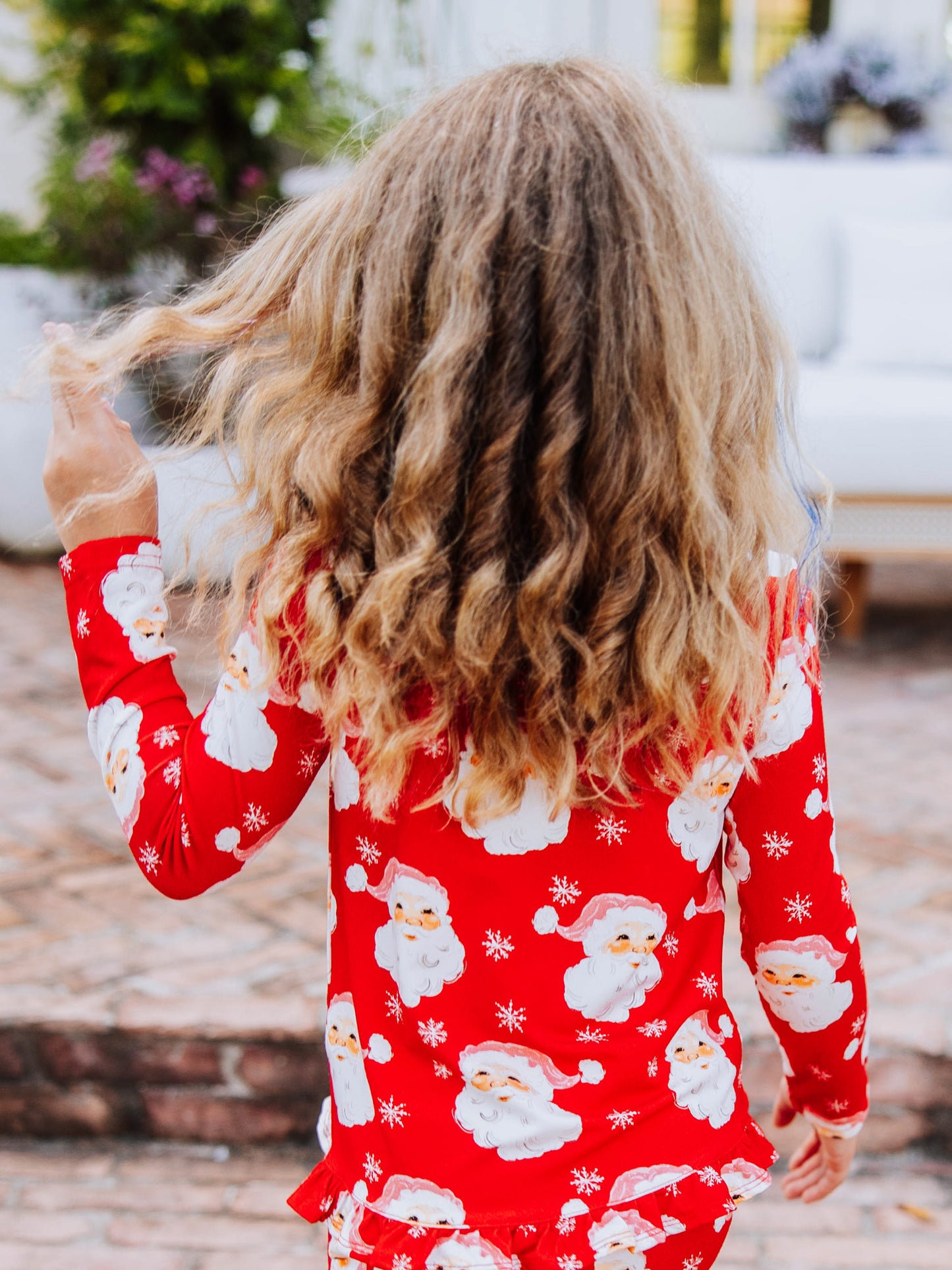 Back side of girl in red santa set. girl is twirling her hair. 