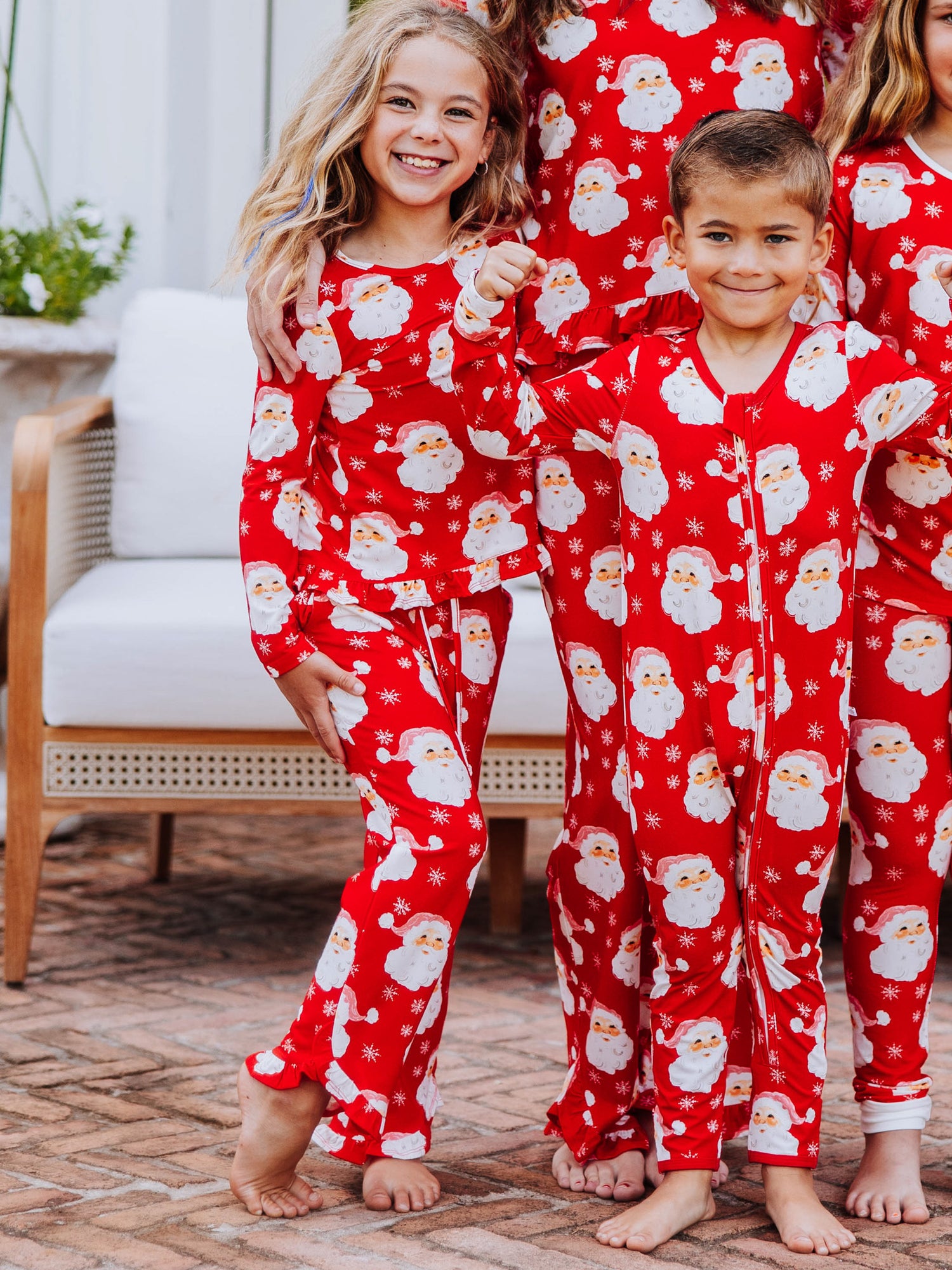 Family photo of everyone wearing the same printed outfits that are red with white santa heads all over them.