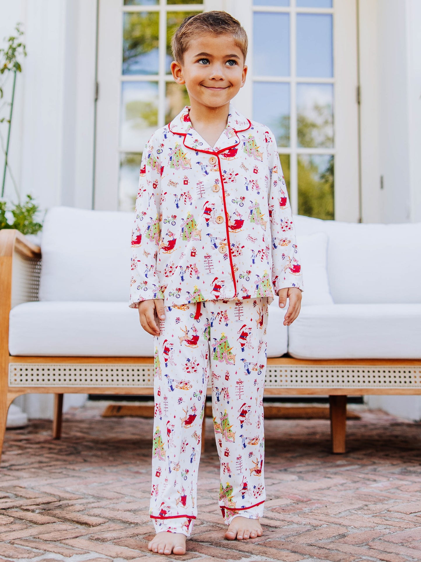Boy standing outside in front of white couth wearing a christmas pattern button set