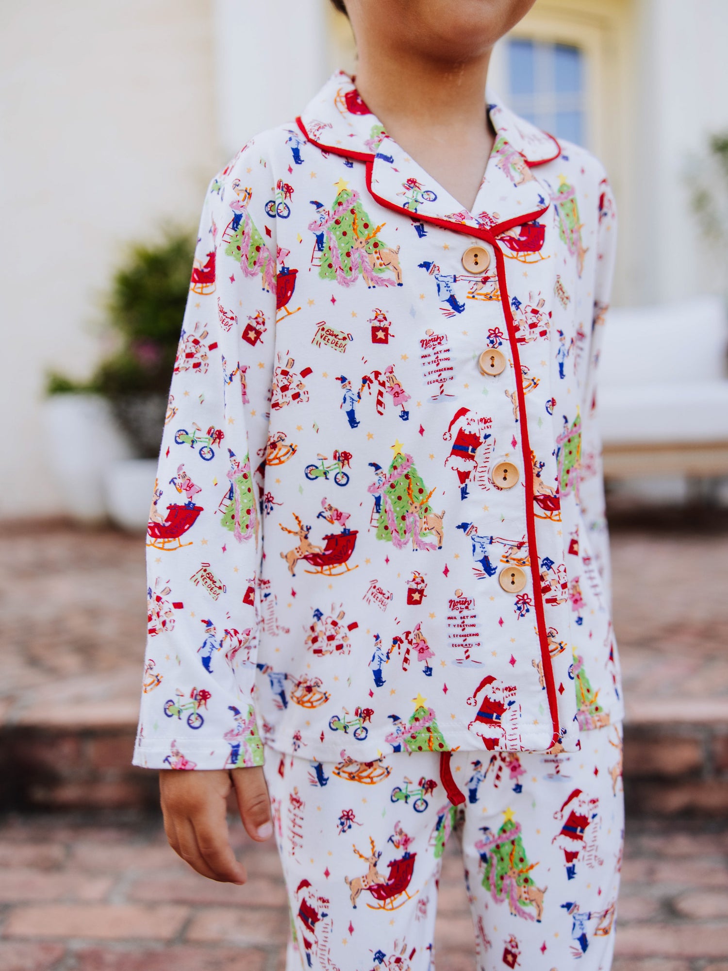 Boy standing outside in front of white couth wearing a christmas pattern button set