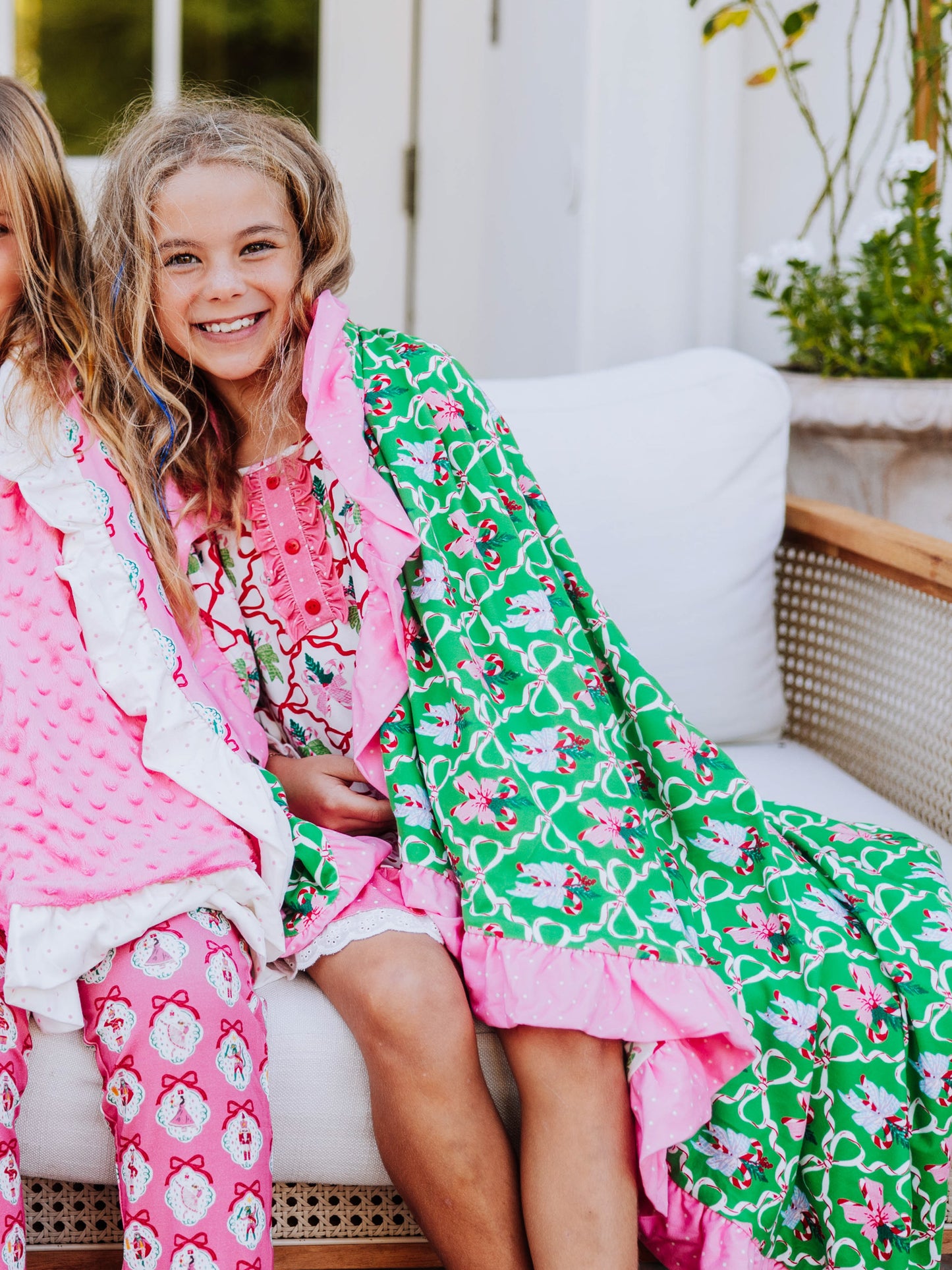 Girl sitting on couch with colorful green, pink, and red blanket wrapped around her. 