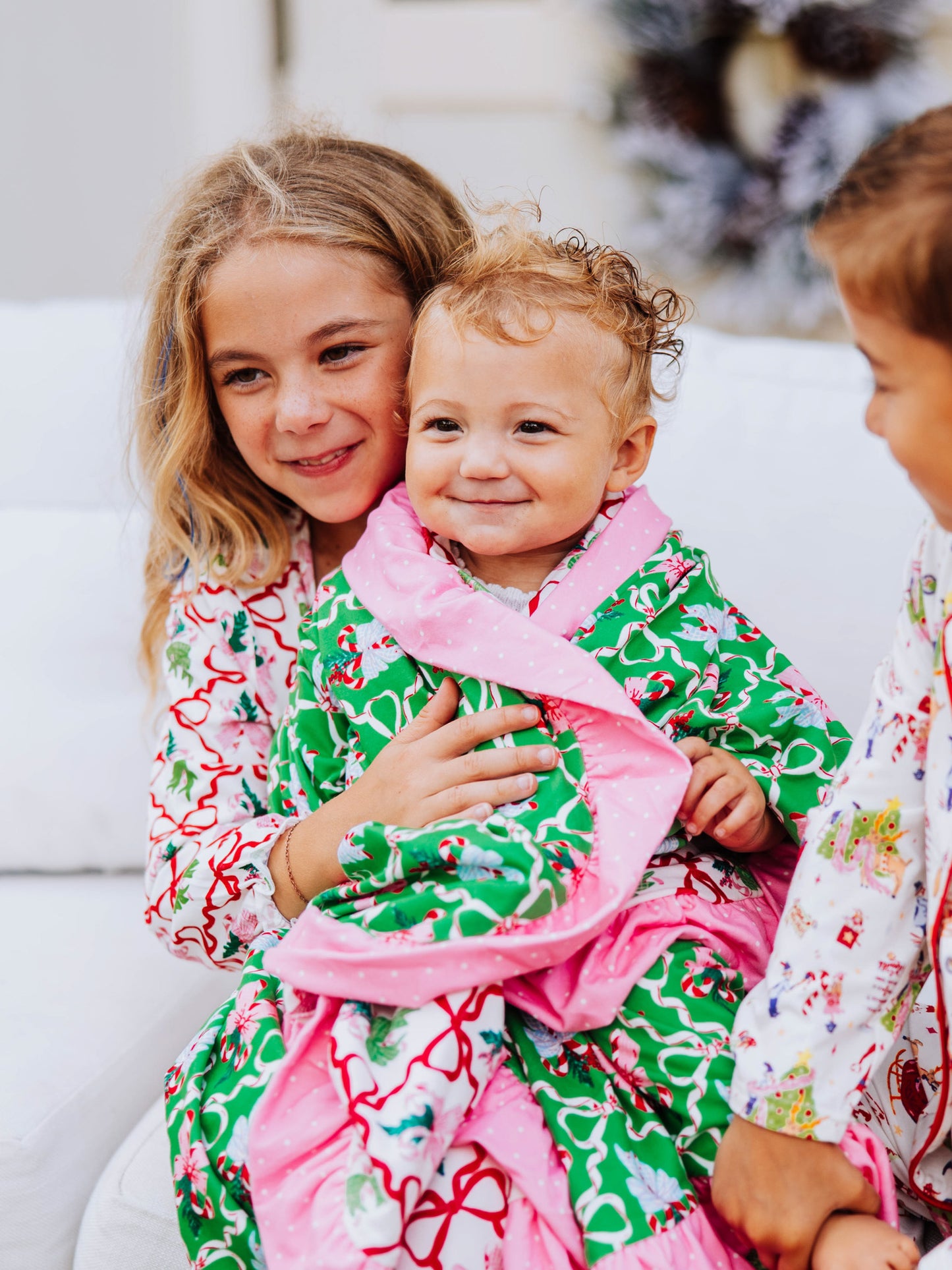 Girl holding a baby that is wrapped up in colorful blanket. 
