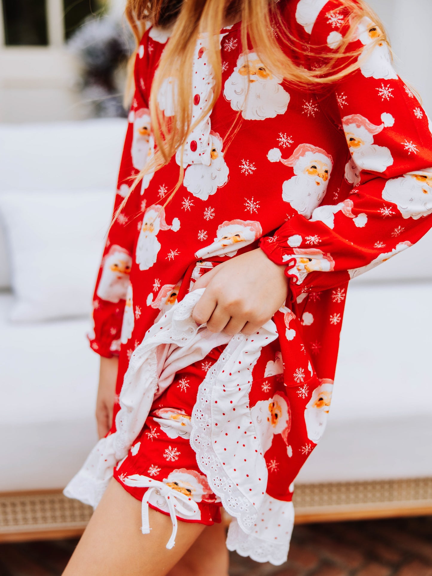 Girl holding up the side of a red santa dress to show the matching bloomers underneath