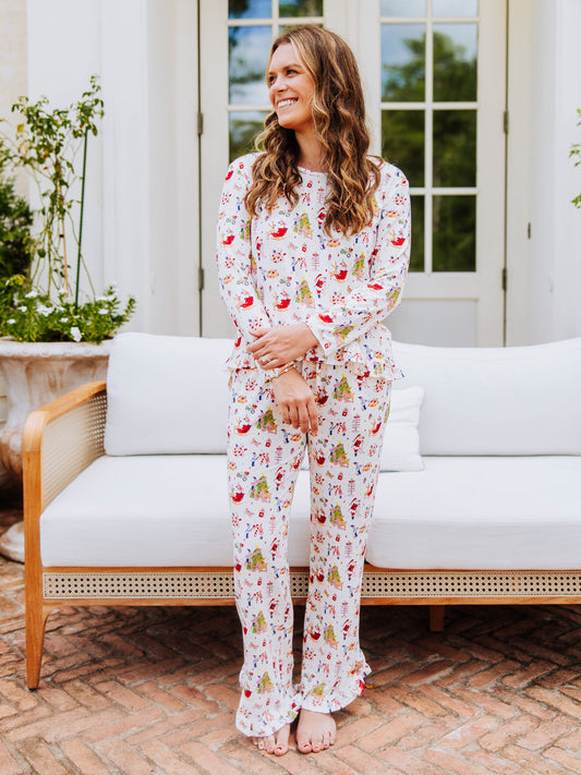 Girl standing outside in front of white couch wearing a ruffled pant set in a north pole pattern. 