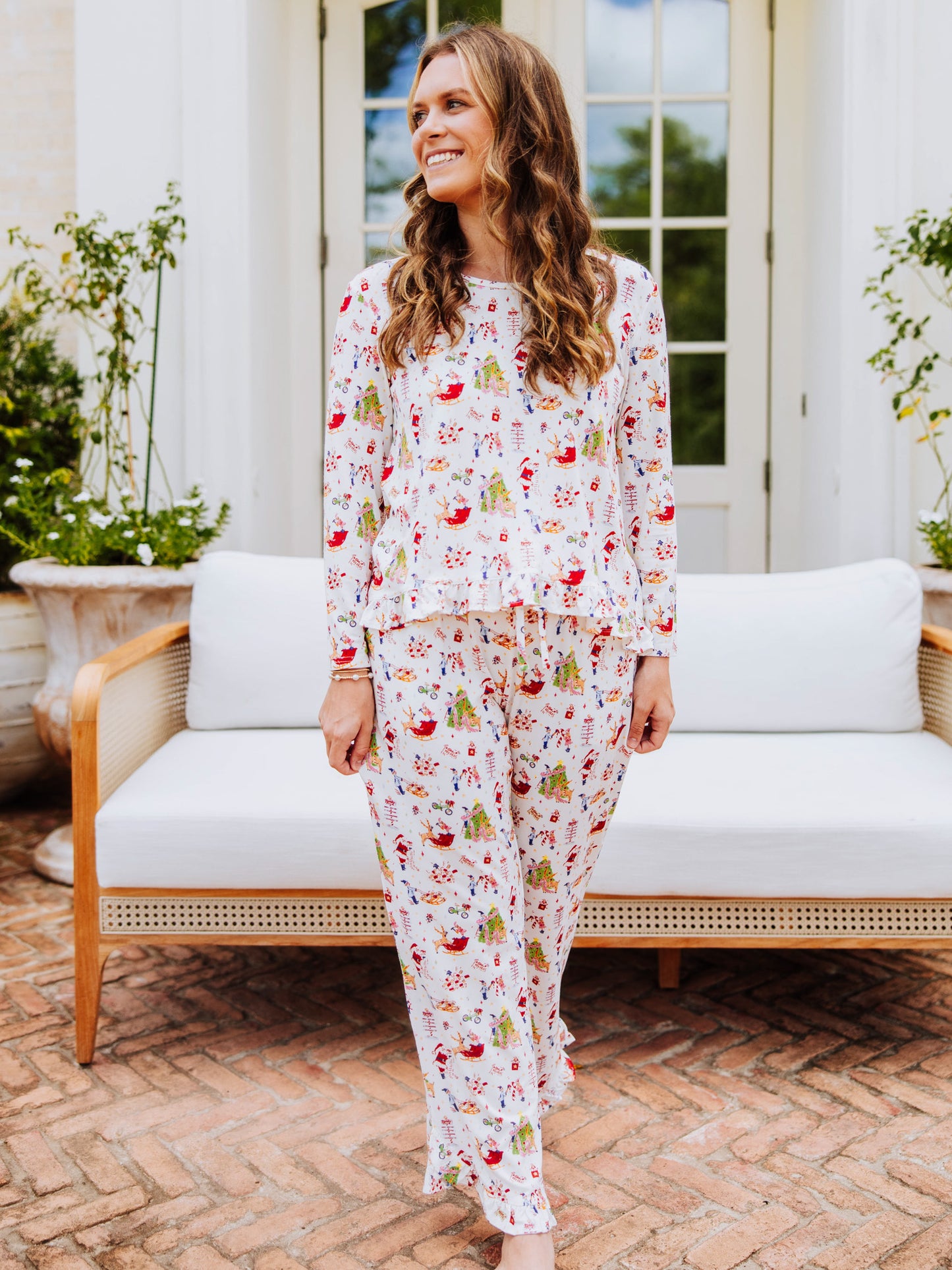 Girl standing in front of a white couch outside wearing a north pole printed ruffled pant set. 