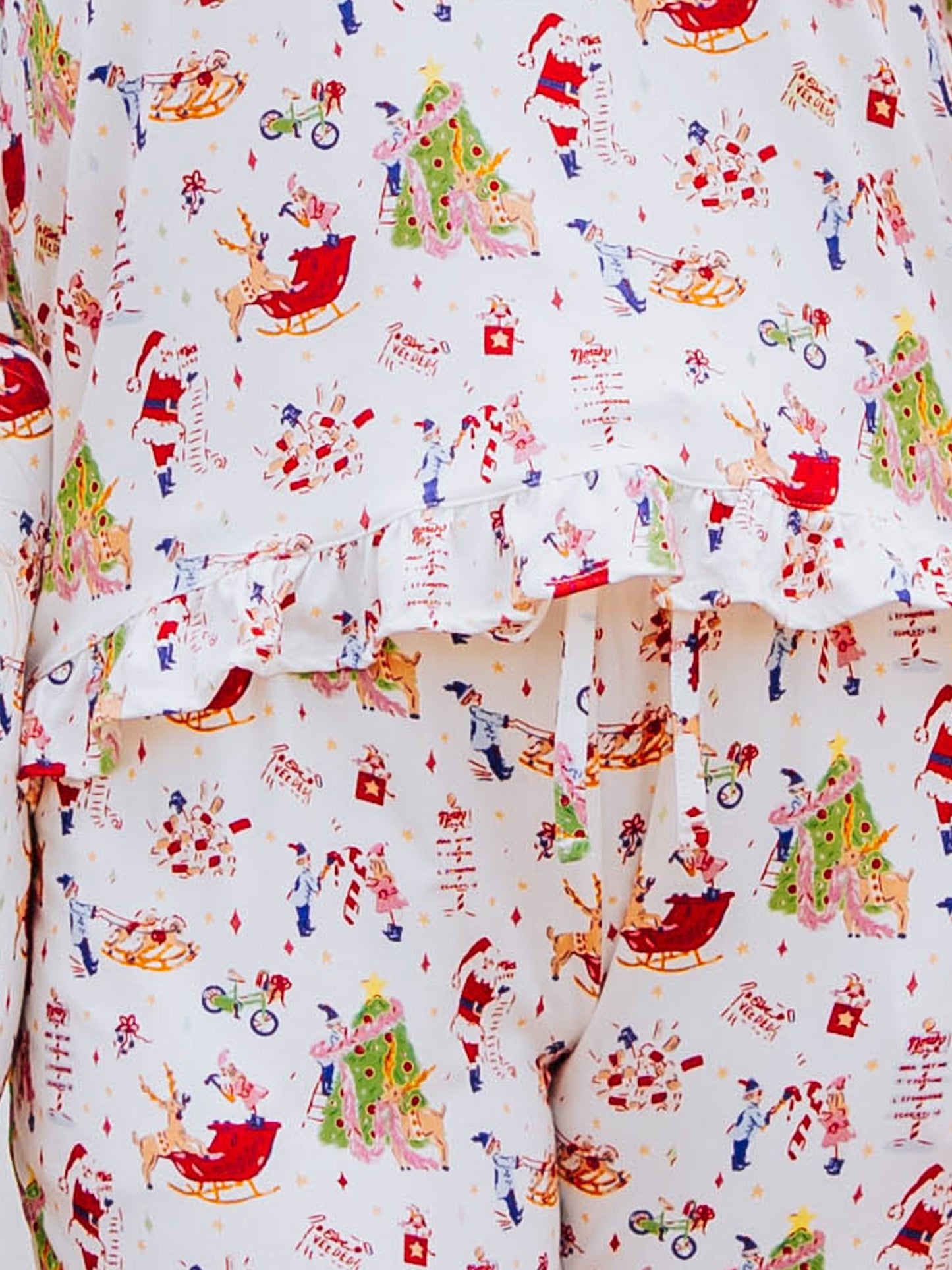 Up close detail shot of Girl standing outside in front of white couch wearing a ruffled pant set in a north pole pattern.  Shirt has ruffles at the bottom
