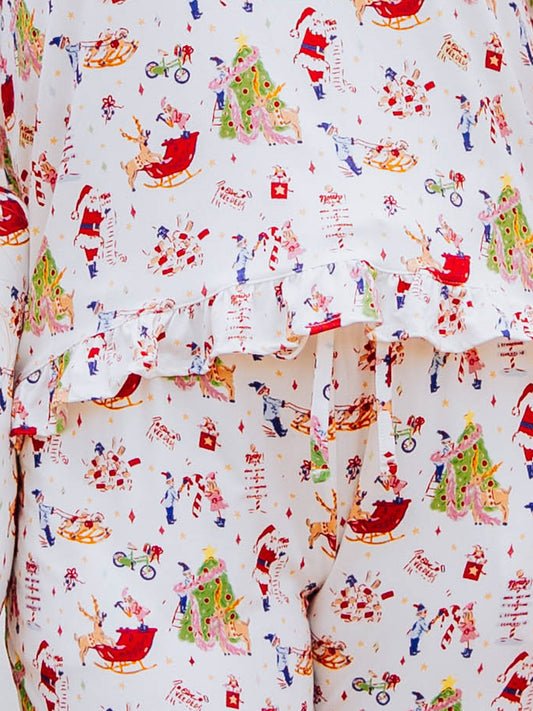 Up close detail shot of Girl standing outside in front of white couch wearing a ruffled pant set in a north pole pattern.  Shirt has ruffles at the bottom