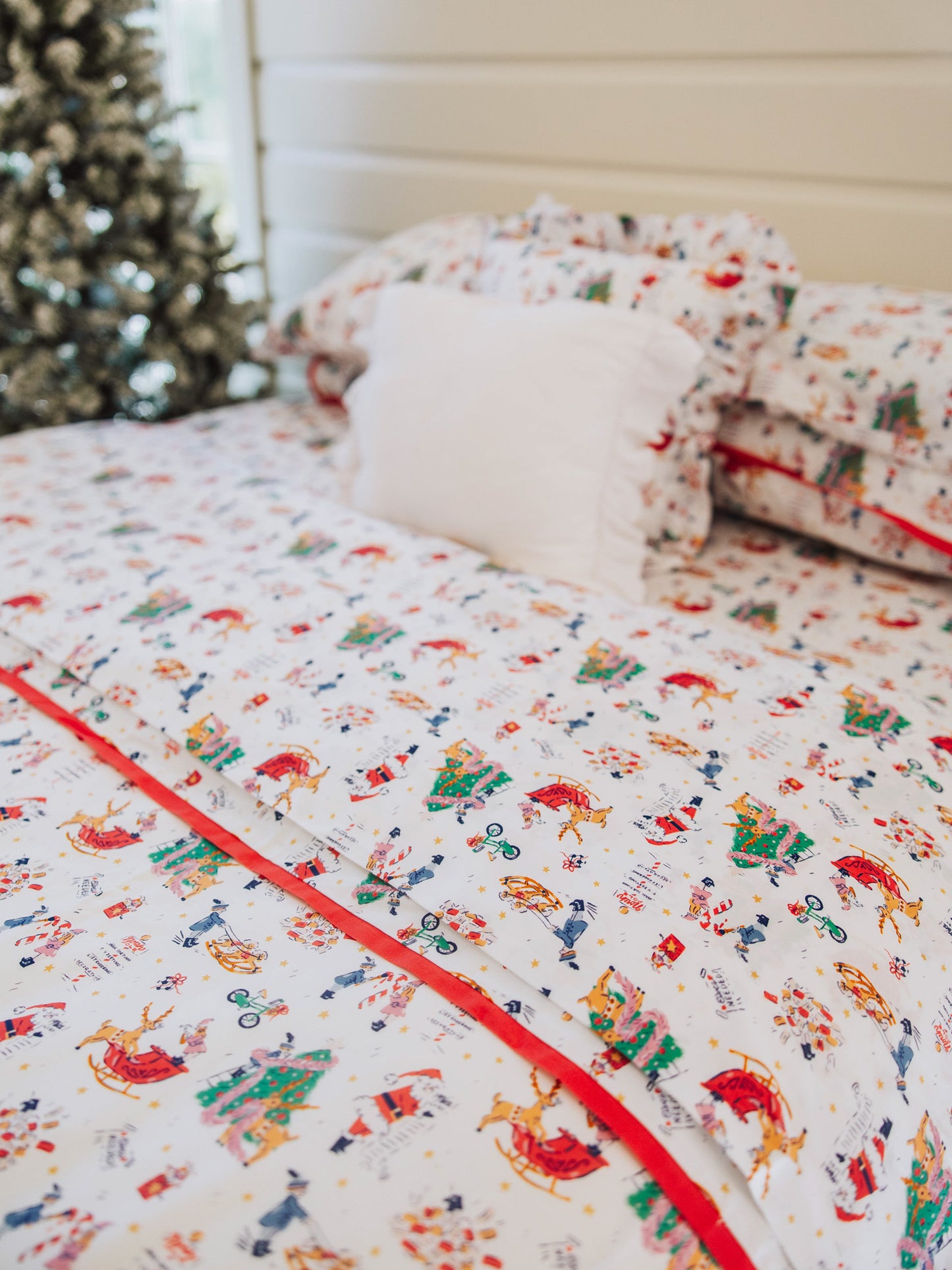 Holiday themed bedding with Christmas tree in background. 