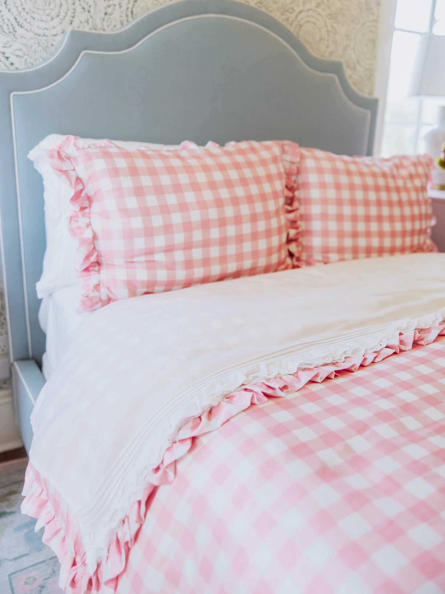 Pink check duvet and pillow cases with white lace sheets. 