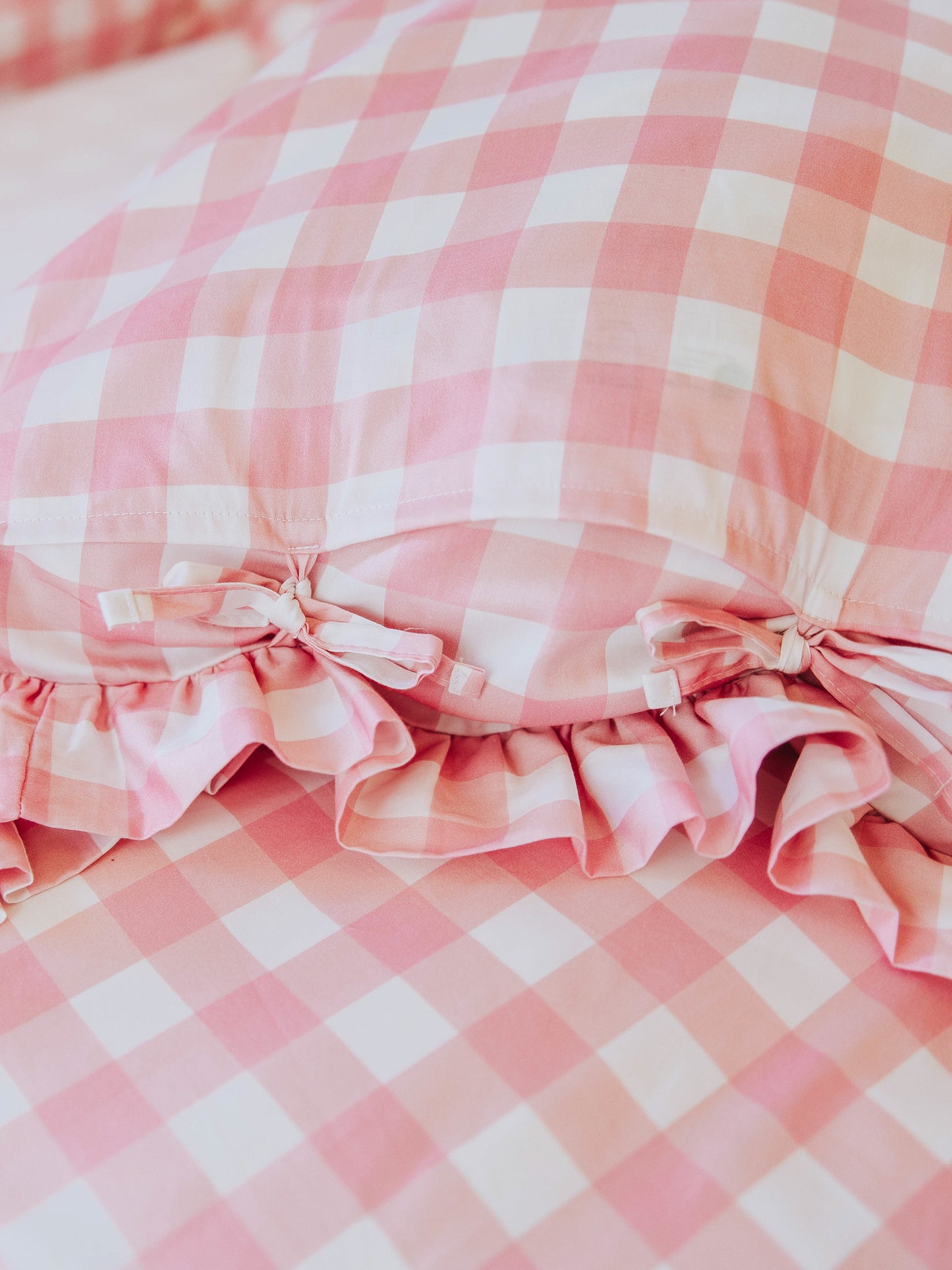 Up close picture of tie closures on pink check pillow case. 