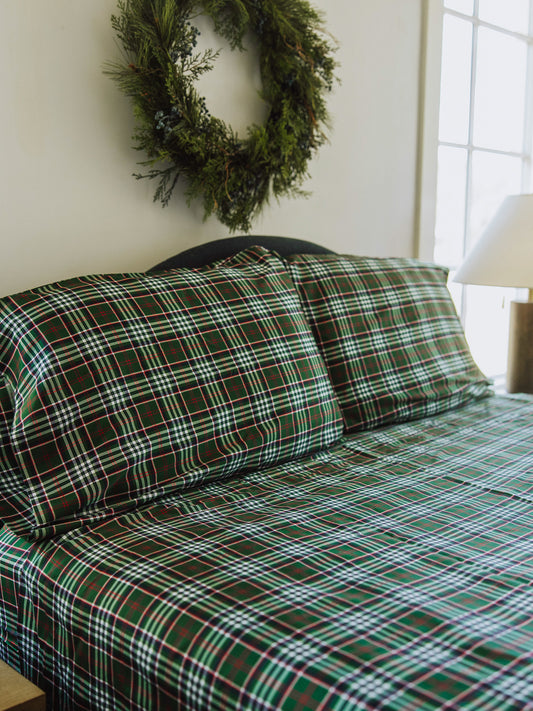 Traditional green plaid sheets and pillow cases on made up bed. 