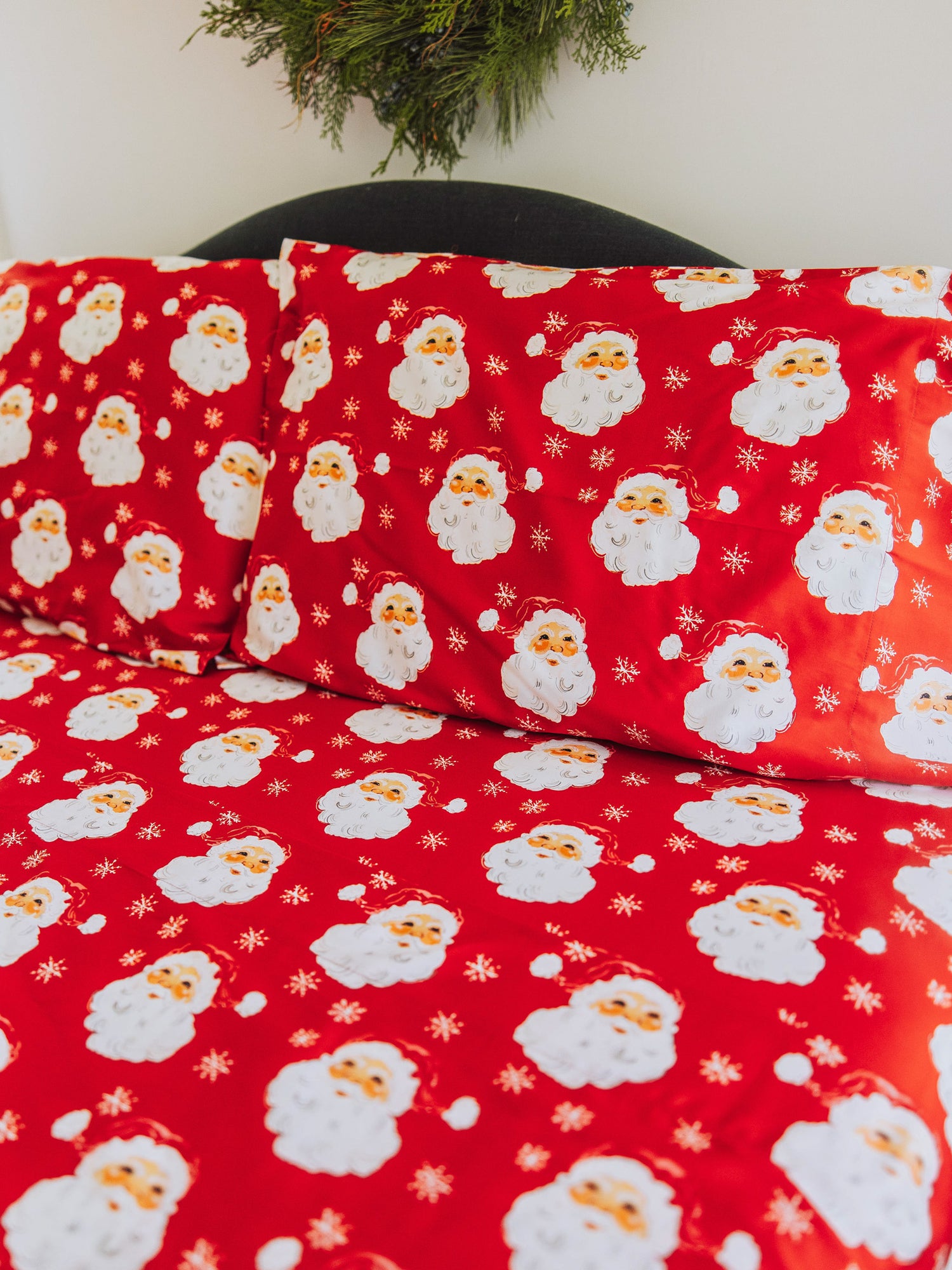 Santa themed sheet set with matching pillow cases on bed. 