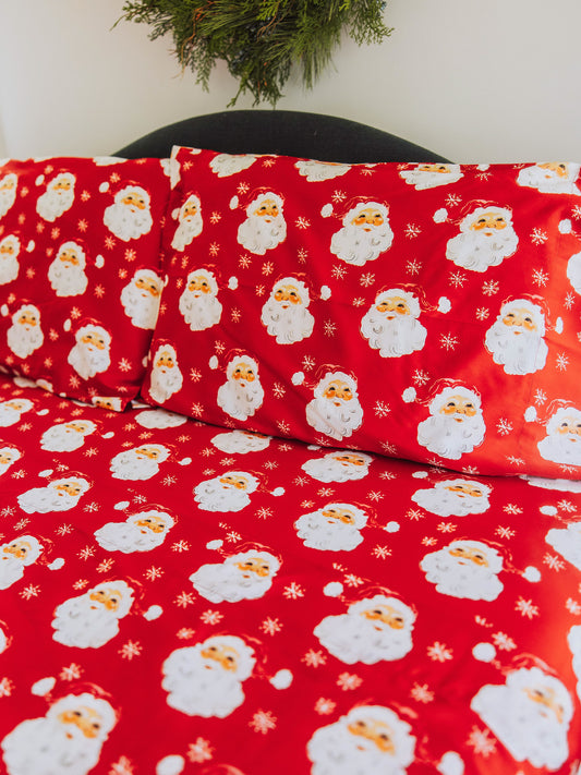 Santa themed sheet set with matching pillow cases on bed. 