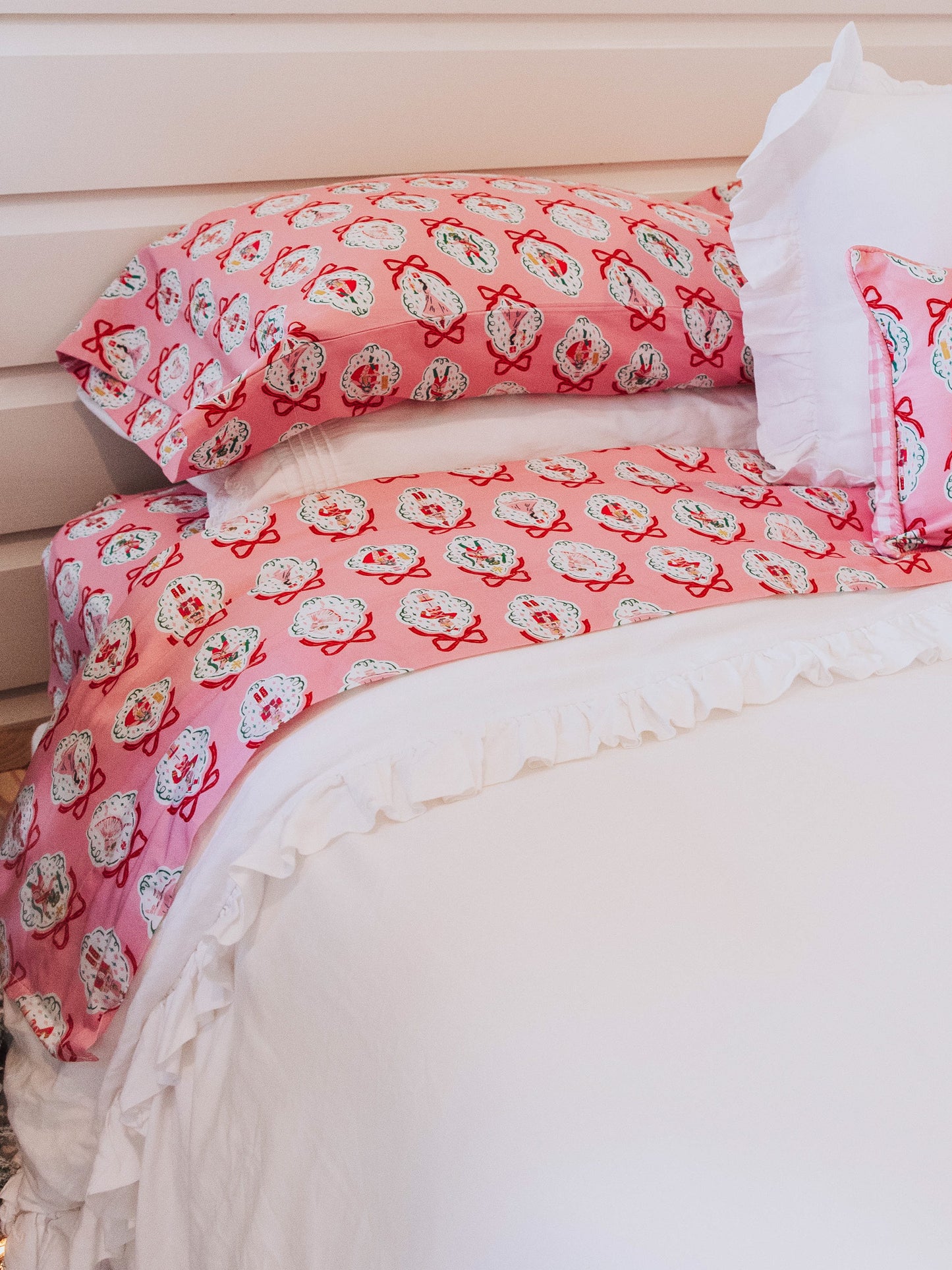Pink nutcracker sheets shown on white duvet. 